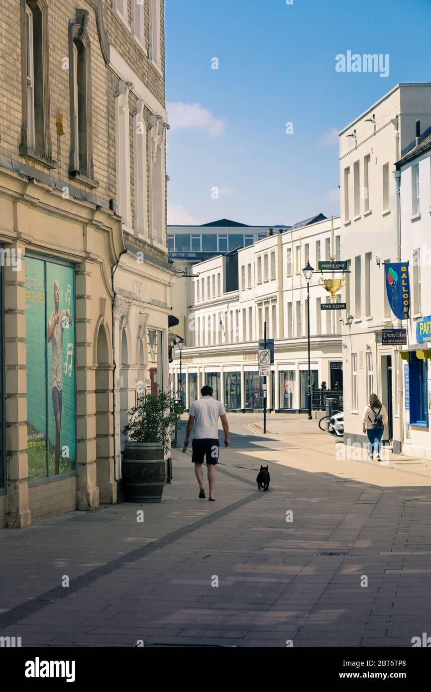 Cheltenham Gloucestershire UK May 21st 2020 A dog walker on a bright sunny day in the quiet town centre during coronavirus outbreak lockdown Stock Photo