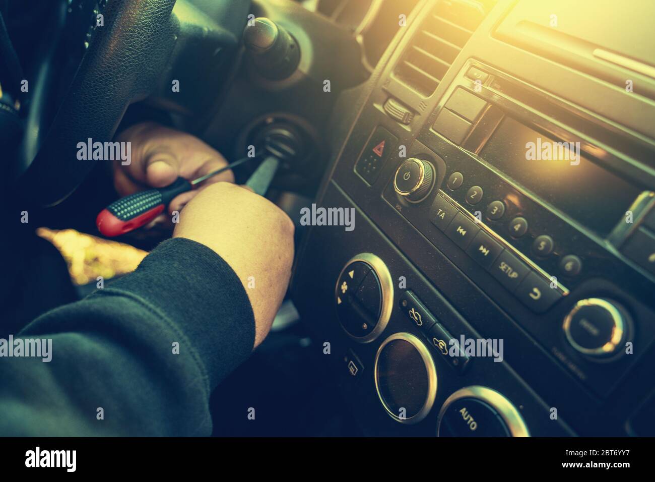 Criminal breaks the car ignition lock to steal auto, close up. Car