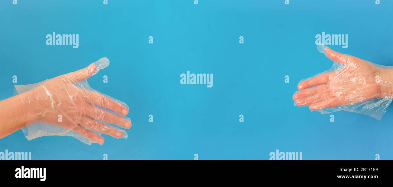 Hands with plastic gloves before a handshake with copy space on blue background Stock Photo