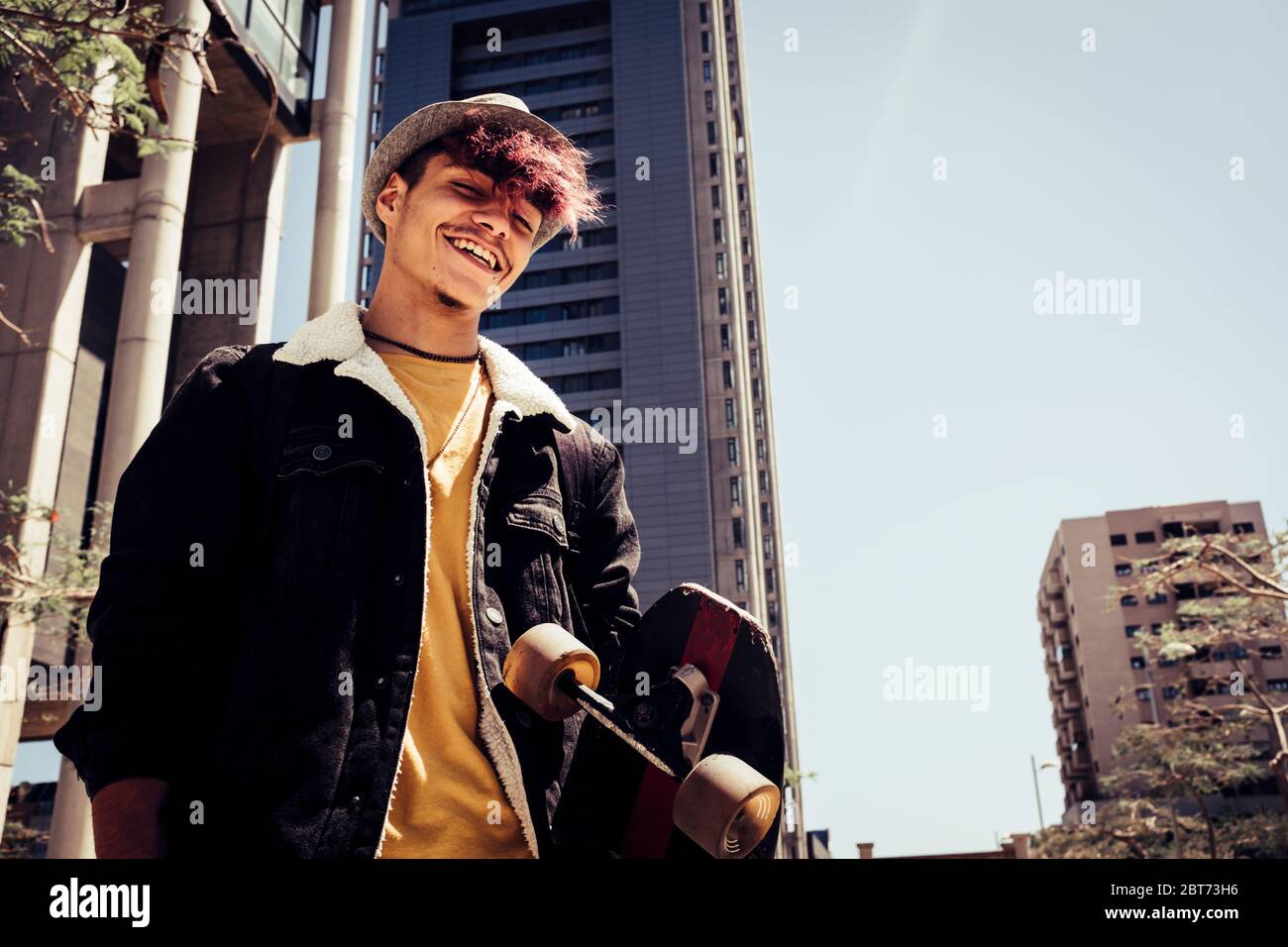Urban style generation z young teenager portrait with city skyline in bakground - alternative and diversity people concept with handsome coloured hair Stock Photo