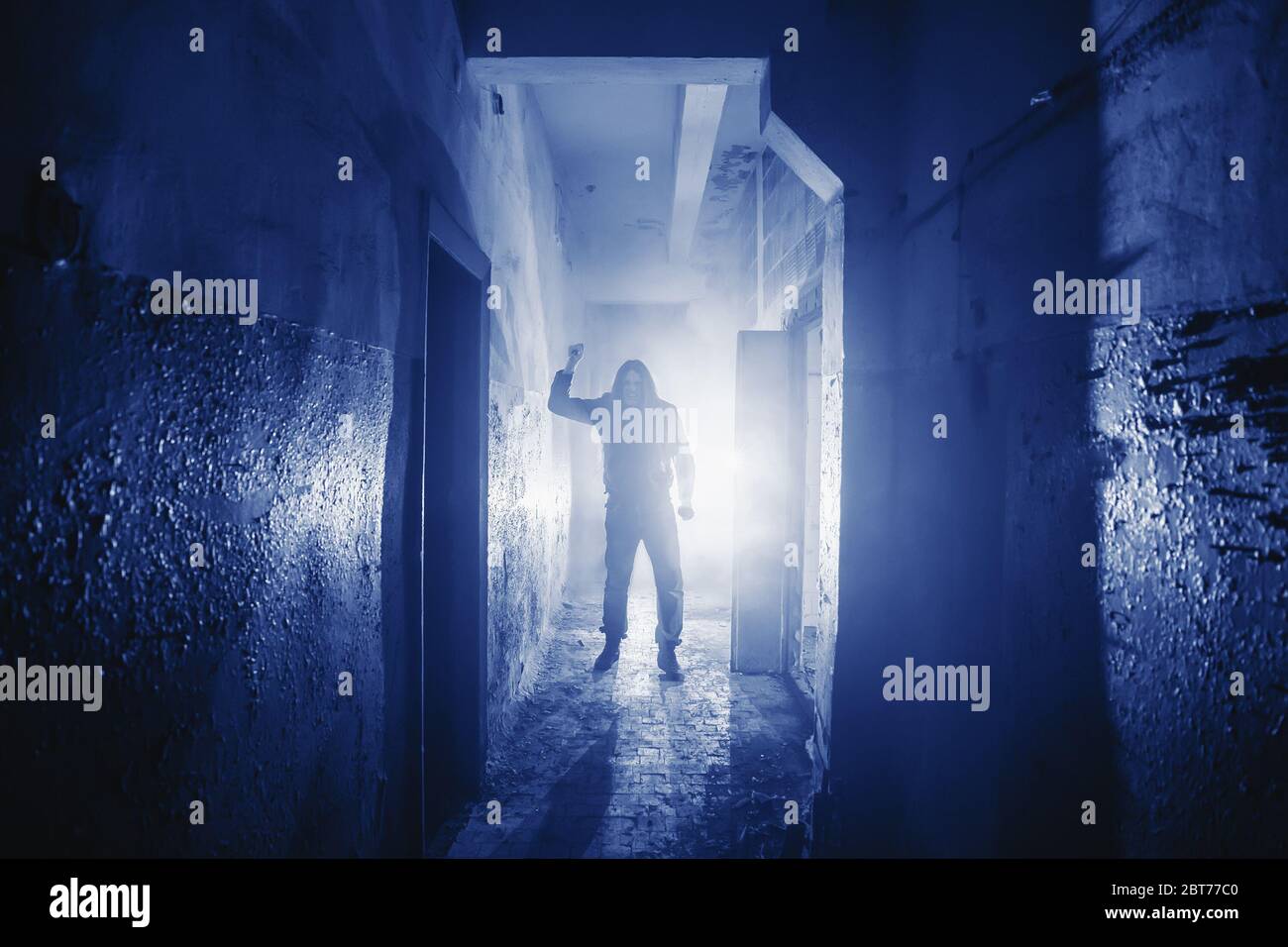 Dangerous Murderer or killer with Knife in hand and light from back in scary corridor in Phantom Blue color toned. Stock Photo