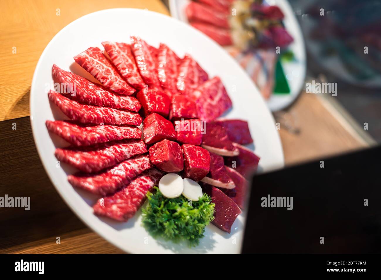 Closeup of plate display outside restaurant with cuts of red raw meat kobe or wagyu beef behind glass window in Tokyo Stock Photo