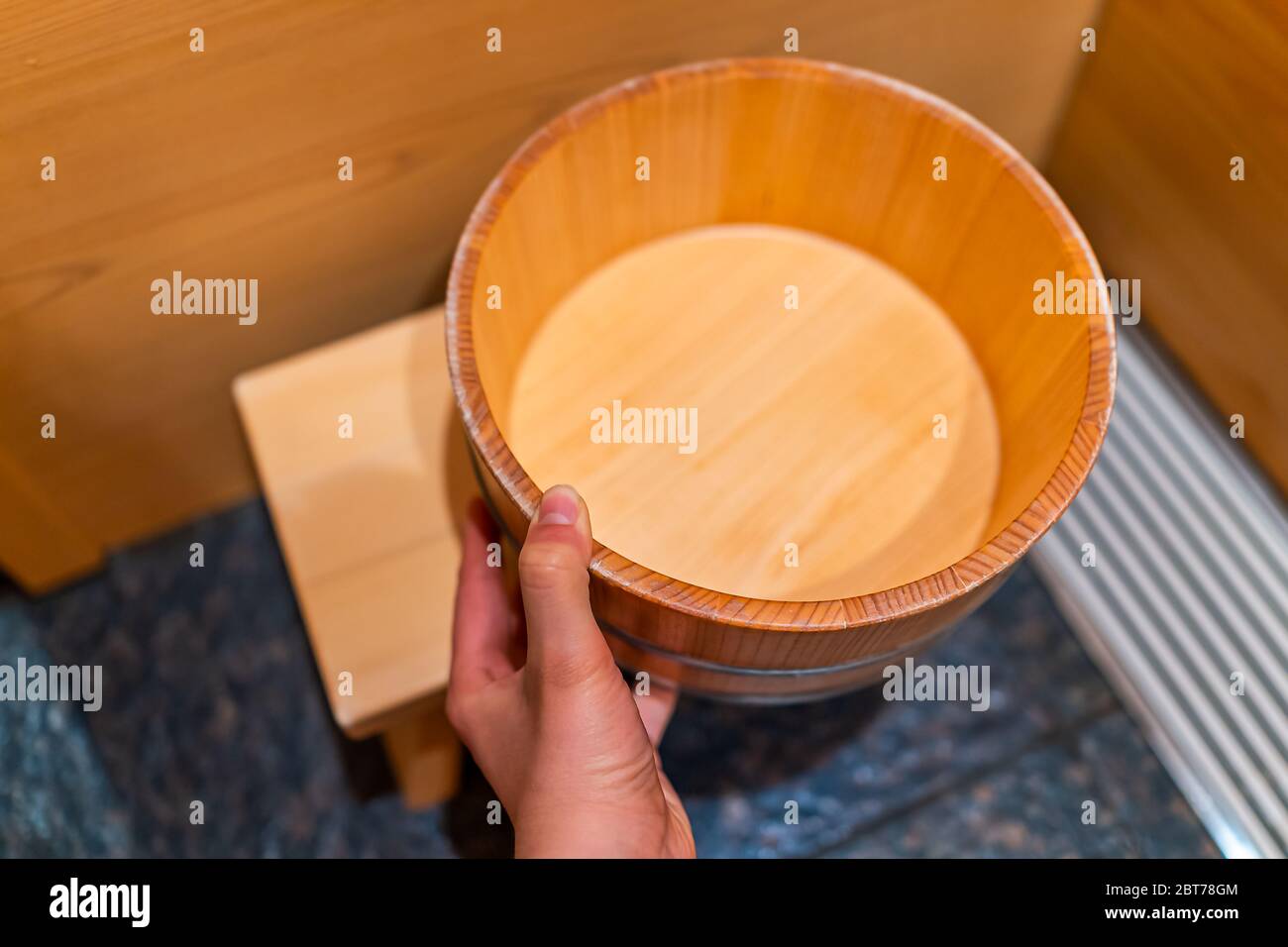 Cypress sauna bathtub and hand holding wooden bucket in traditional Japanese room with water stool in home house or onsen hotel bathroom interior in J Stock Photo