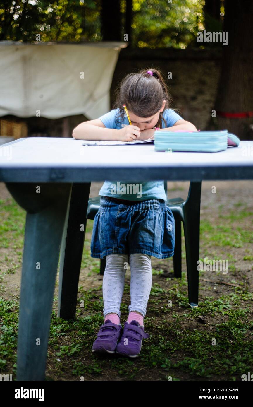 6 year old girl doing homework on home garden table Stock Photo - Alamy