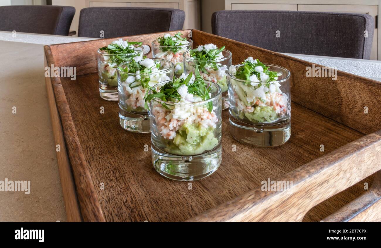 Festive appetizer glasses with avocado mousse and North Sea crab on a wooden tray. Stock Photo