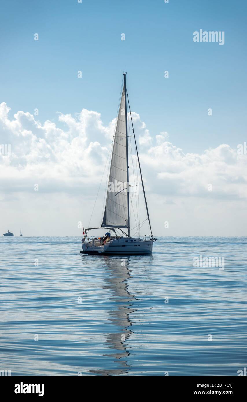 Sailing boat on the sea sails reflect on a calm water summer day Stock Photo