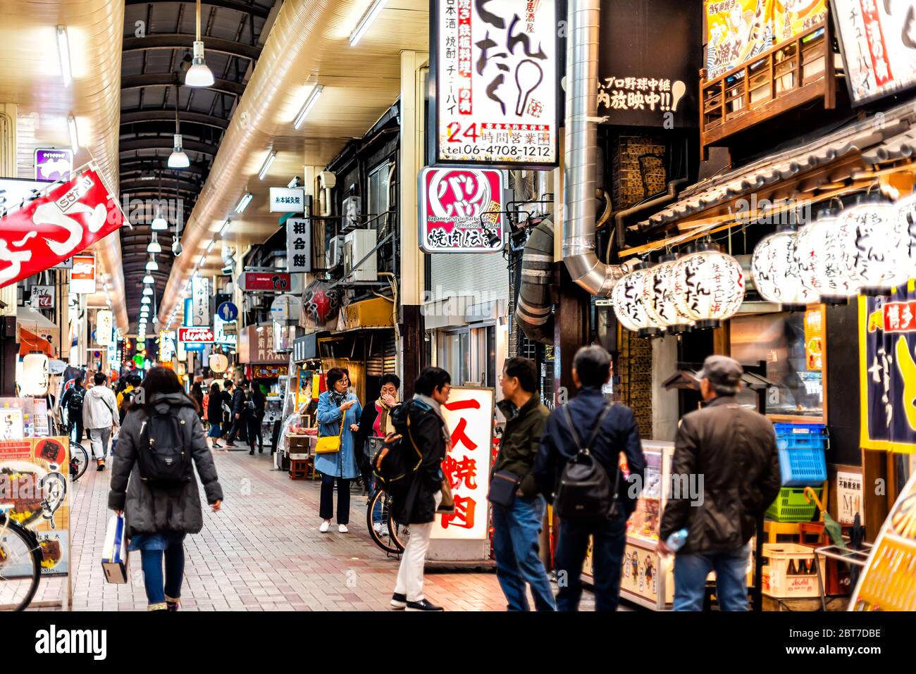 Osaka, Japan - April 13, 2019: Inside famous arcade covered street with people walking shopping with many signs at evening night with food restaurants Stock Photo