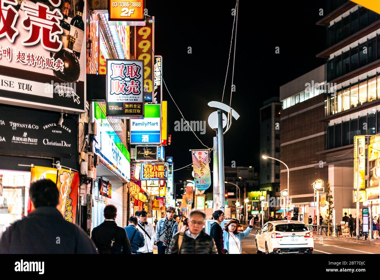 Tokyo, Japan - April 3, 2019: Shinjuku downtown with street and people walking by izakaya restaurants at night and signs near Okubo station on road Stock Photo