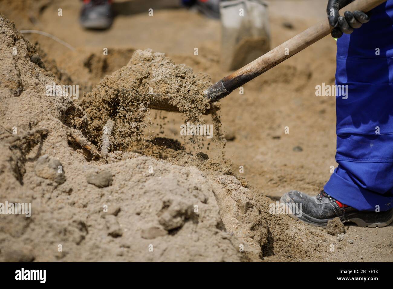 Details with a construction worker using a shovel to load sand in a wheelbarrow. Stock Photo
