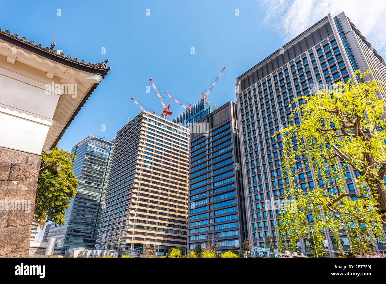 Tokyo, Japan - April 1, 2019: Moat surrounding wall by Imperial palace during spring day with cityscape skyscrapers in downtown park construction cran Stock Photo