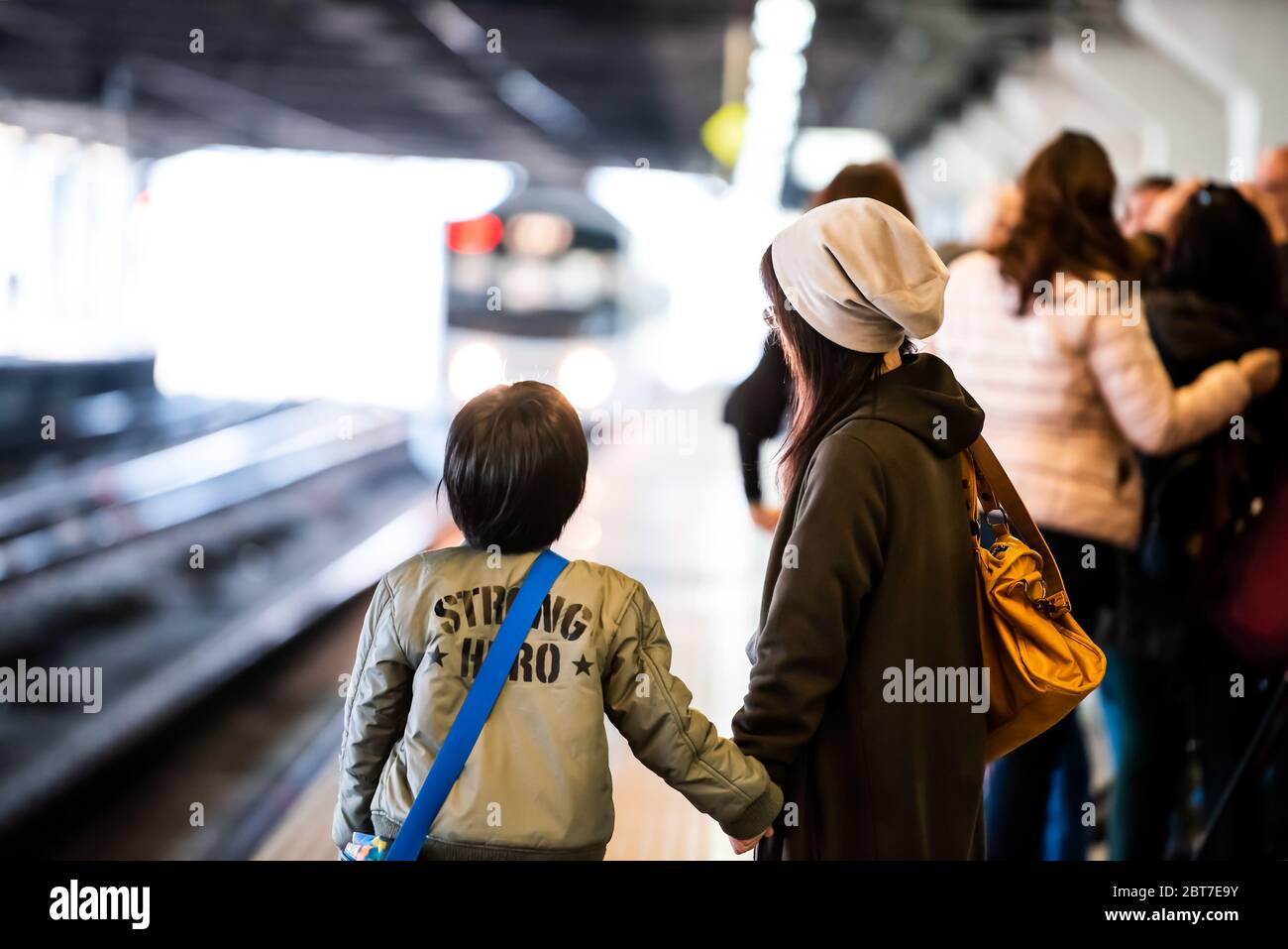 Utsunomiya, Japan - April 5, 2019: JR Train station platform local line to Nikko with mother and child local people waiting and incoming headlights Stock Photo