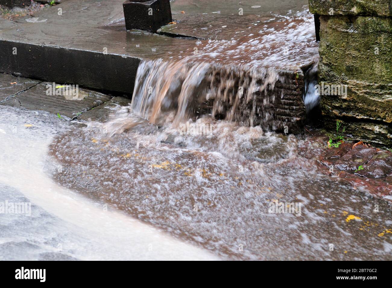 Rainwater pouring down steps on footpath when council surface water drain blocked, UK Stock Photo