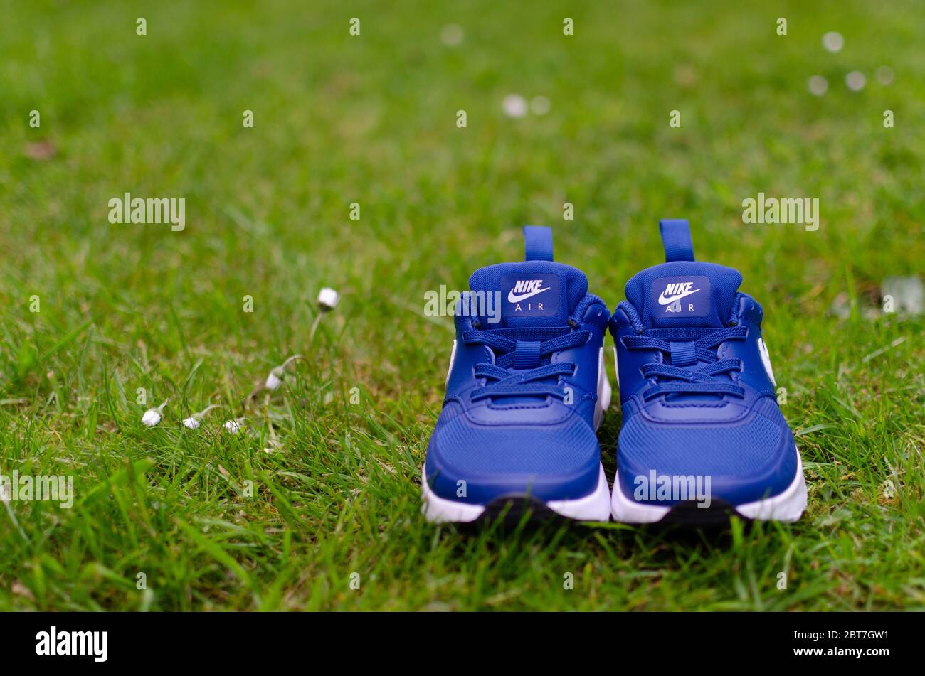 The close up photo of child's pair of blue Nike Air trainers on the vibrant green grass. Shallow field of view was used for imaging. Stock Photo
