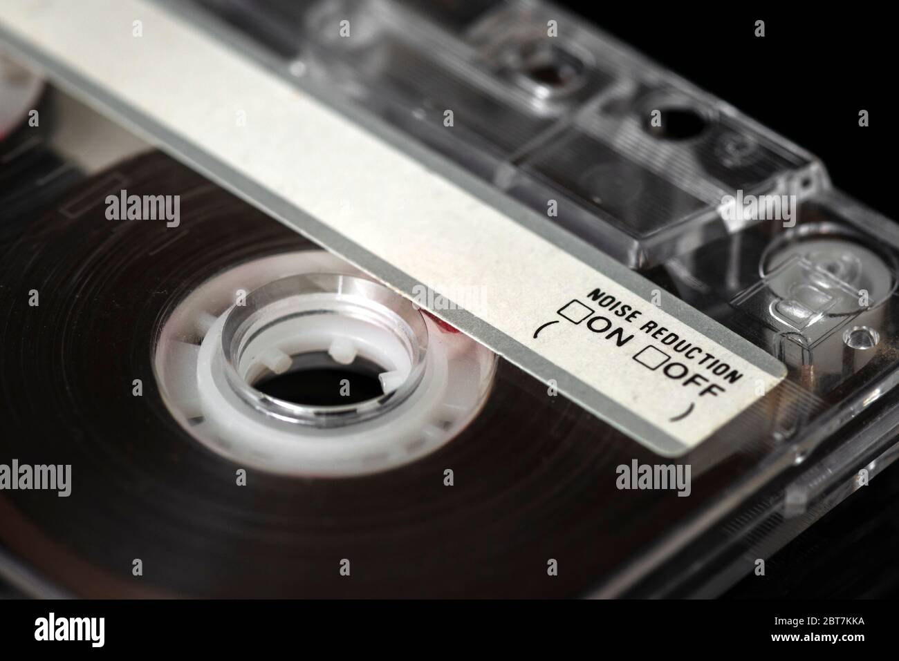 Noise reduction label writing on a classic old audio cassette tape close up isolated on black. Stock Photo