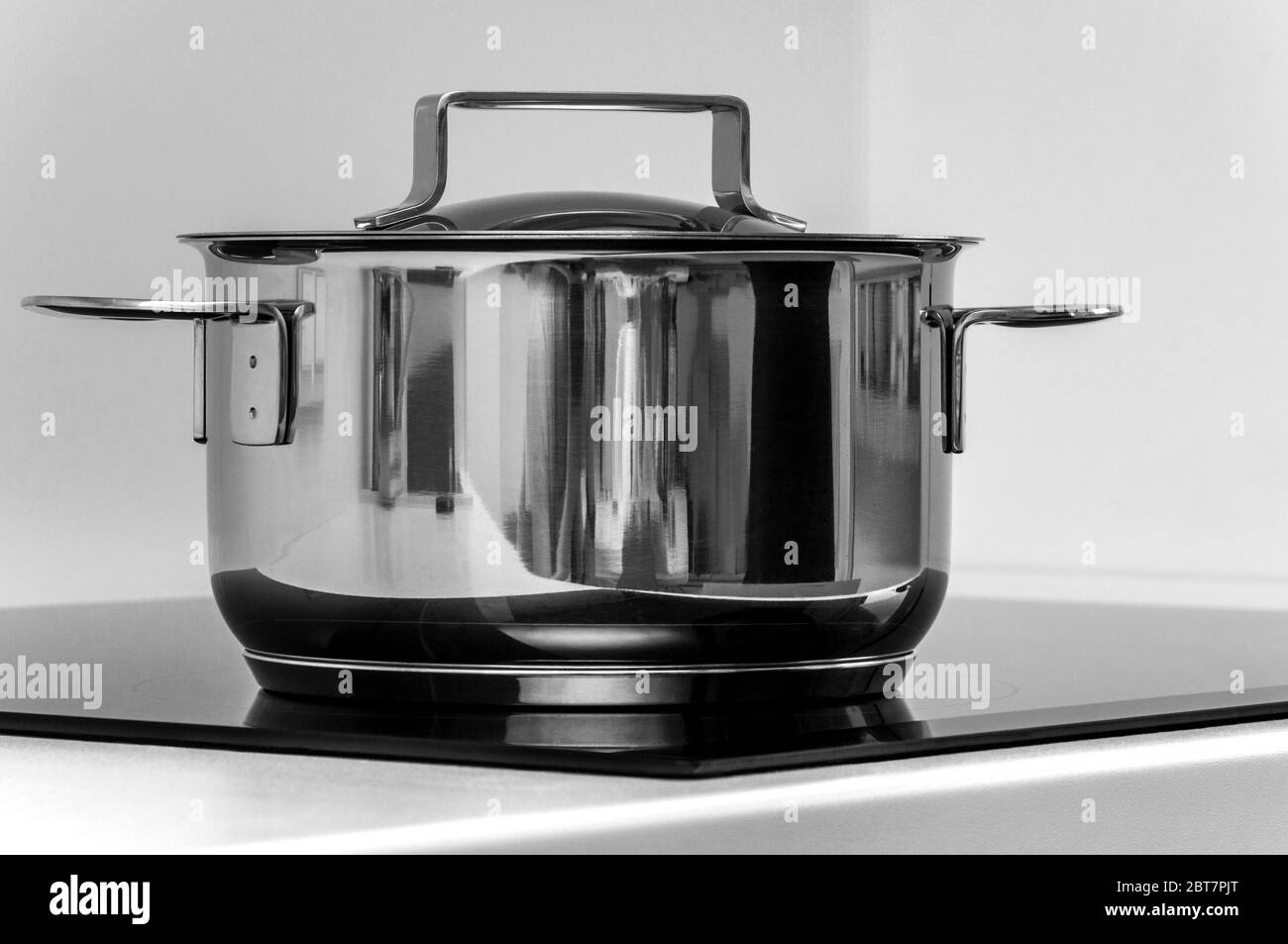 Metal cooking pot on the black induction stove with white background Stock Photo