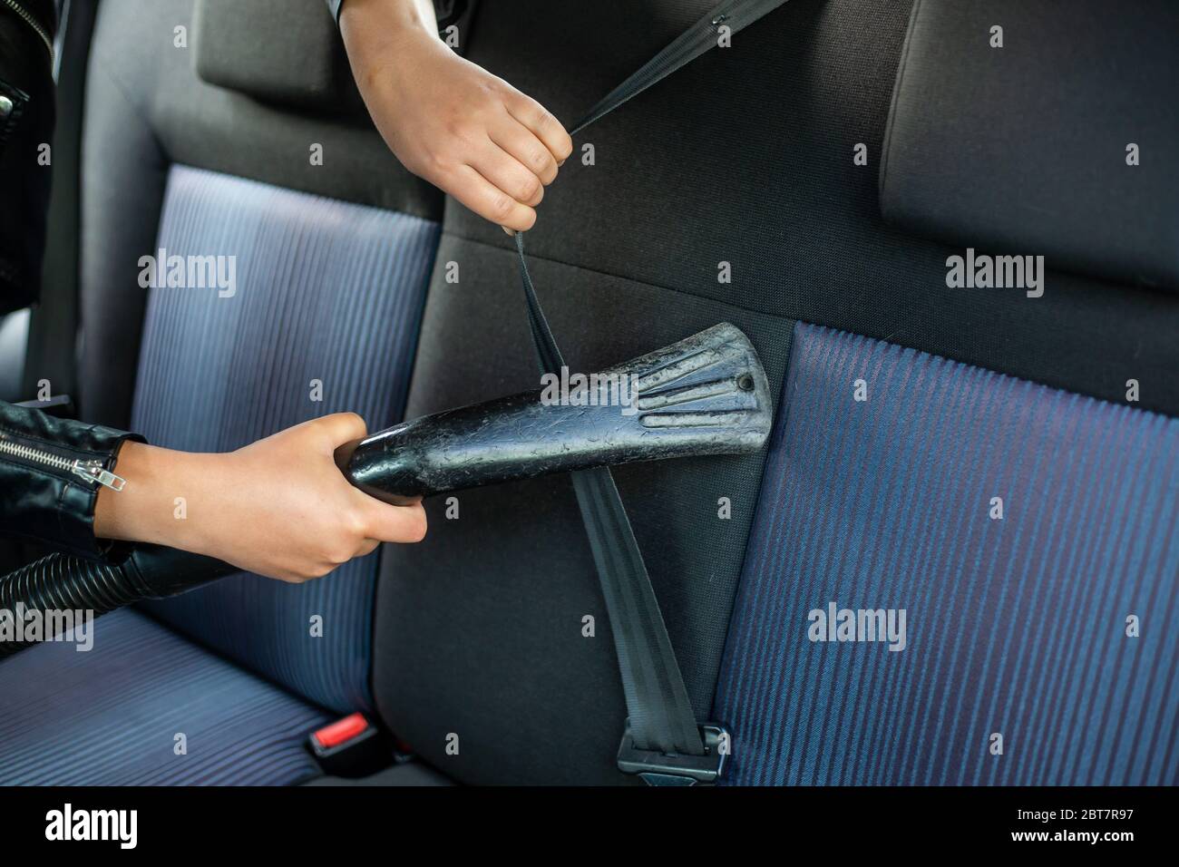 Woman cleaning, vacuuming interior of the car by vacuum cleaner