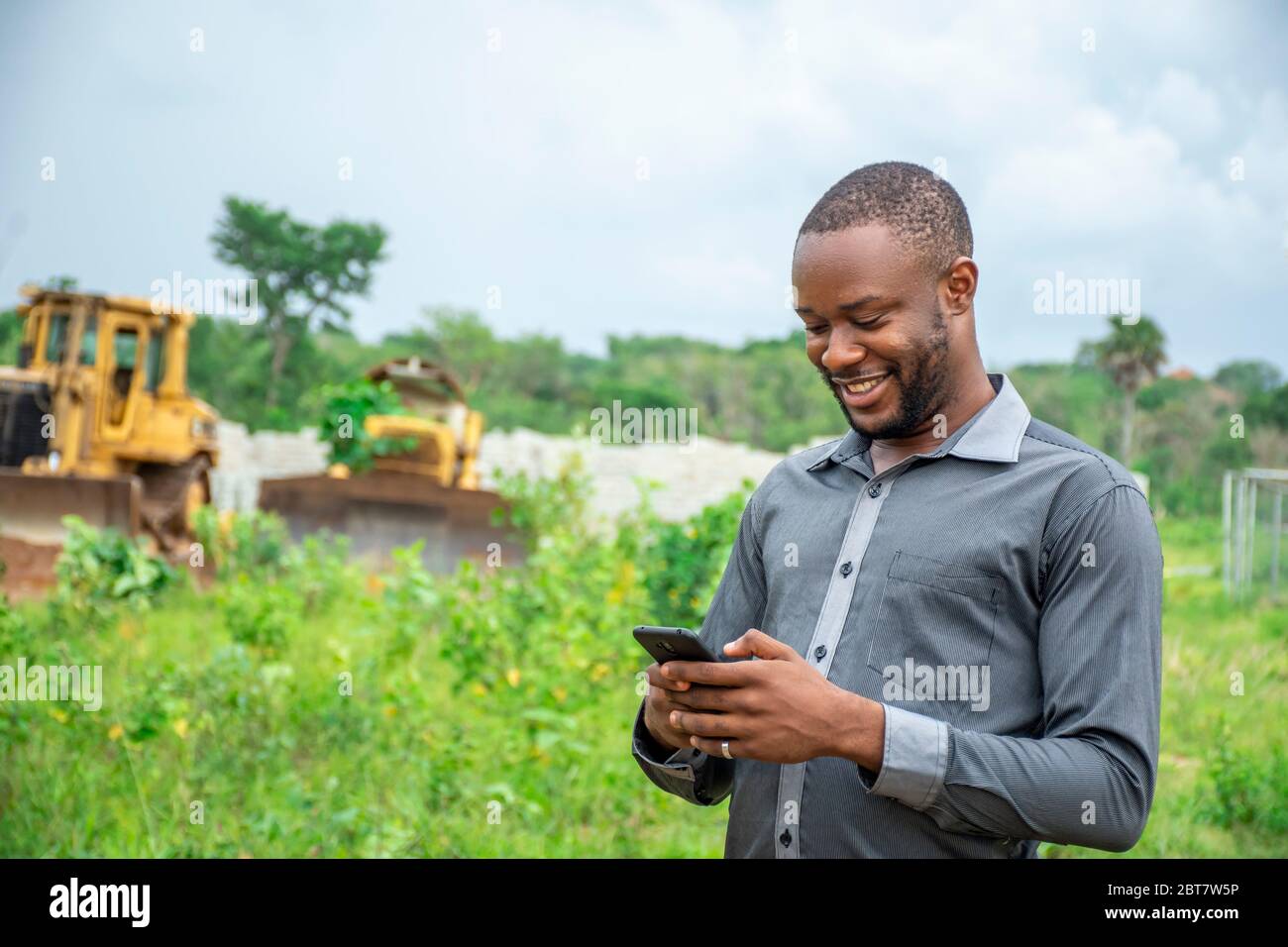african agricultural businessman, using a mobile phone on a plot of land Stock Photo