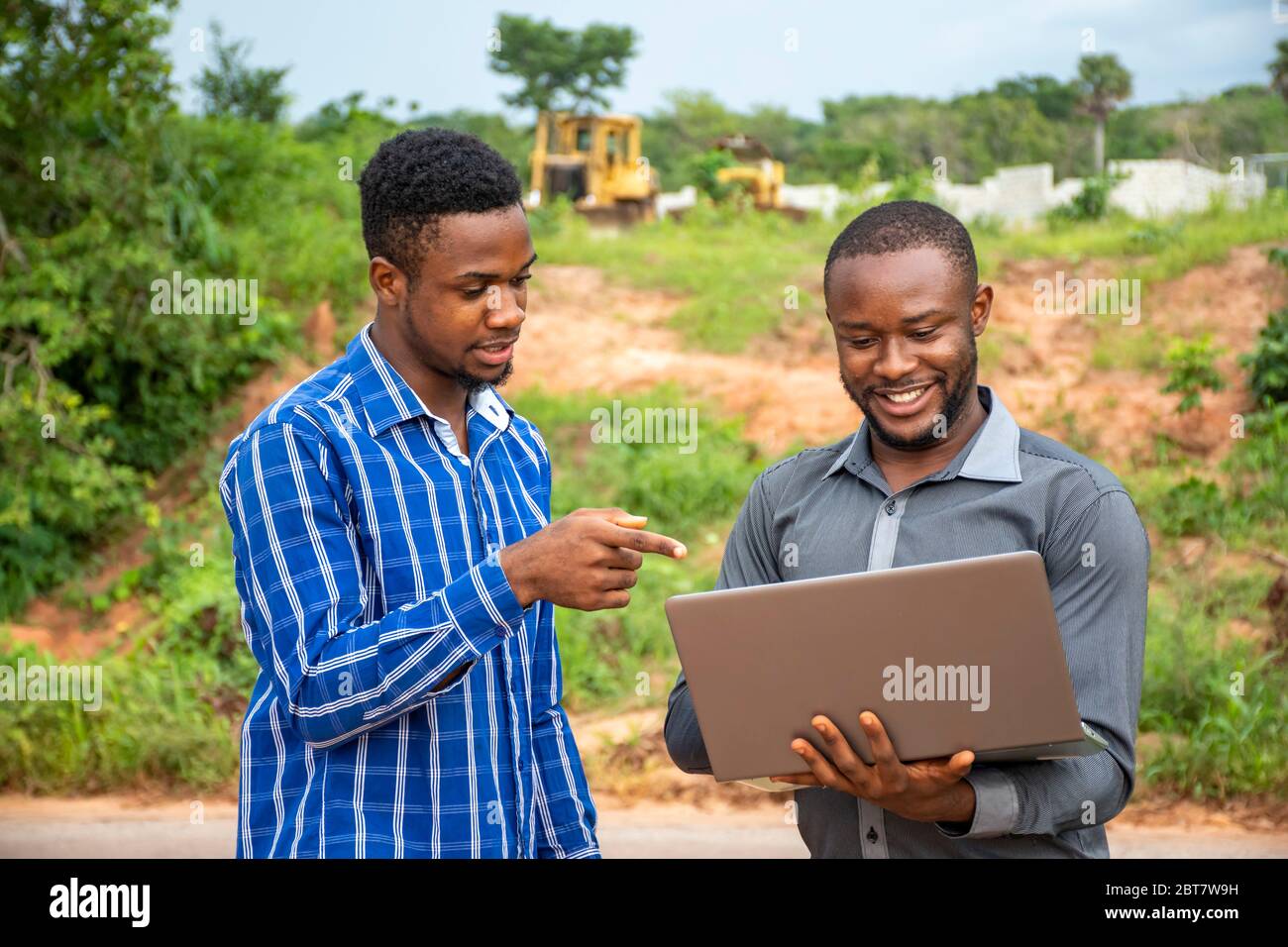 african business men, discussing and surveying a piece of land, using a laptop Stock Photo