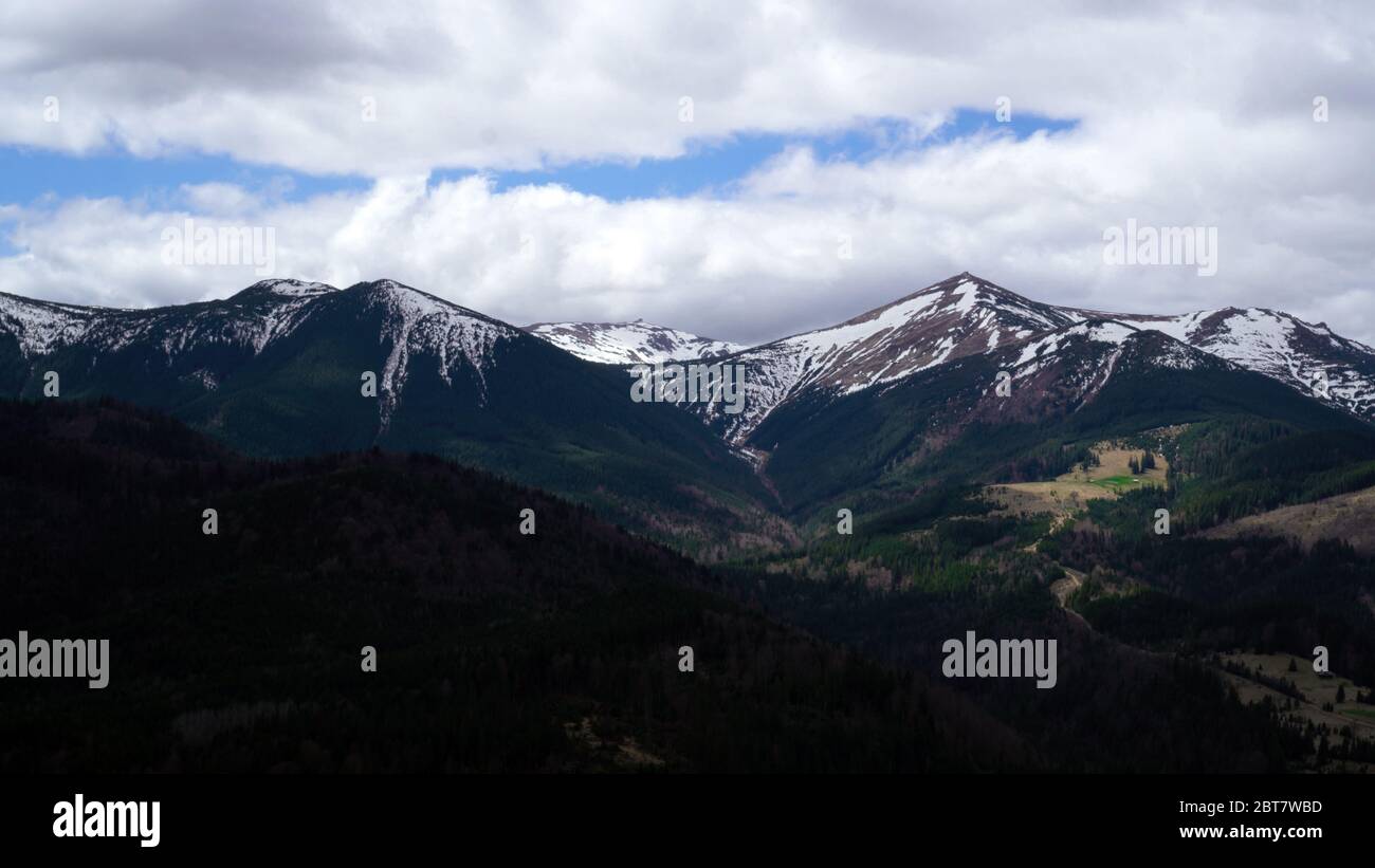 Hiking on Ukrainian Montenegrin snowcapped ridge with white clouds and blue sky. Contrast background. Travel and relax Stock Photo