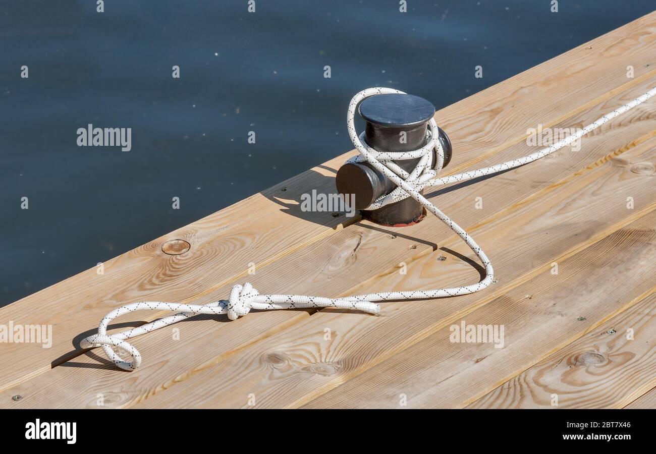 wooden pier at river closeup with rope and mooring post Stock Photo