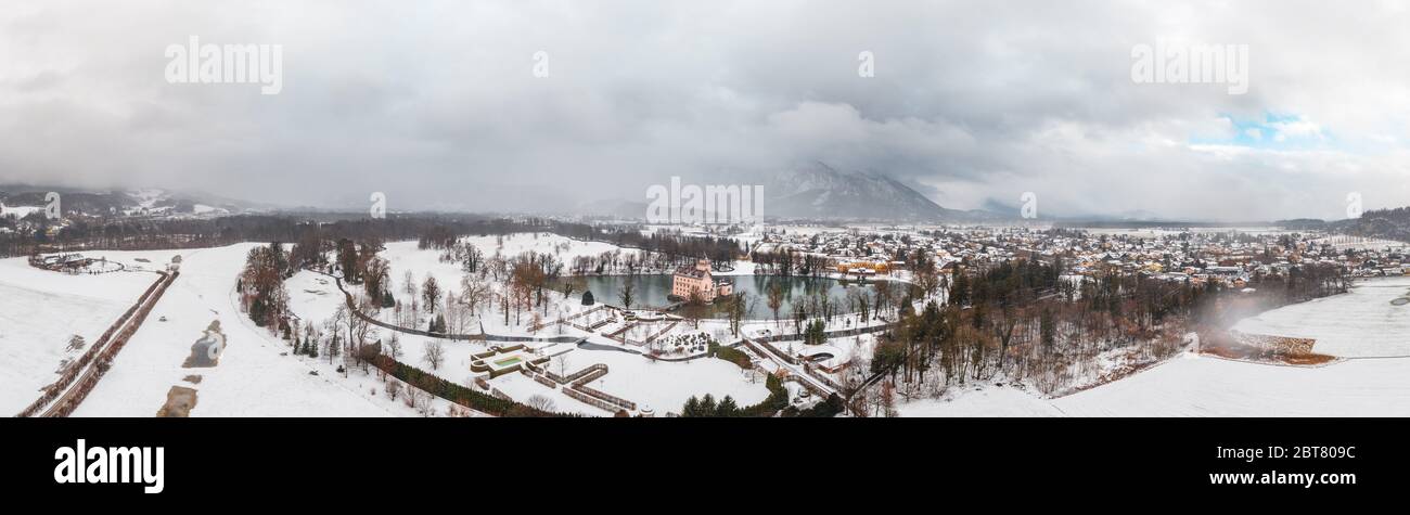 Panoramic aerial view of Schloss Anif moated in artificial pond at Salzburg outskirts in heavy snow during winter view of untersberg snow mountain Stock Photo