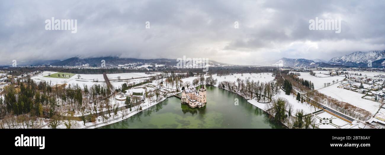 Panoramic aerial view of Schloss Anif castle moated in artificial pond at Salzburg outskirts in heavy snow during winter view of untersberg mountain Stock Photo