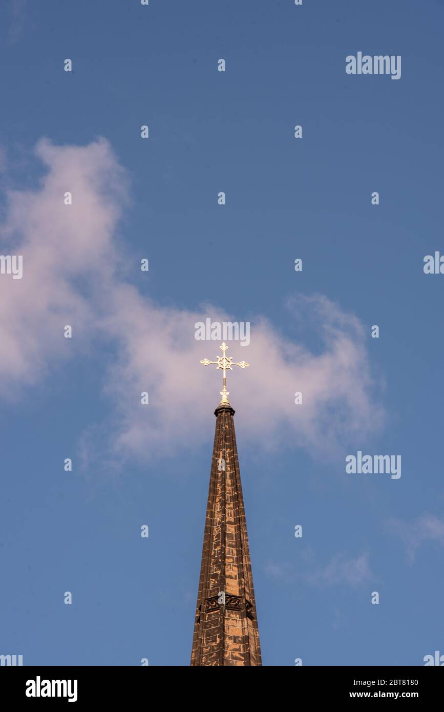 Spire with cross lit by the sun against blue sky of St Johns Church now the Hub on the Royal Mile Edinburgh Stock Photo