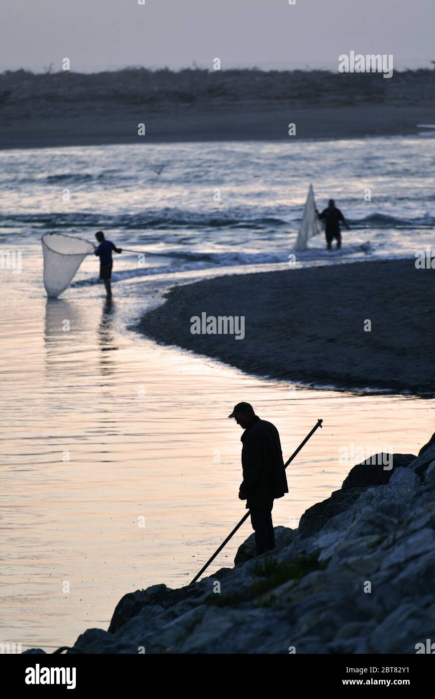 HOKITIKA, NEW ZEALAND, OCTOBER 24, 2019: A man uses a scoop net at sunset for catching whitebait at the Hokitika River on the West Coast of the South Stock Photo