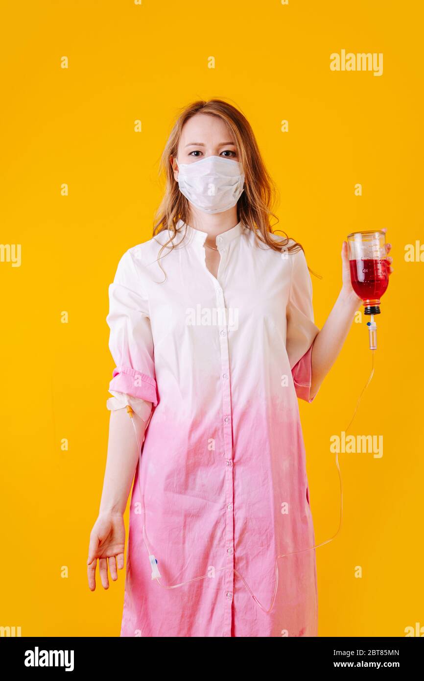 Girl in mask and with a dropper holding a bottle with medicine in hand Stock Photo