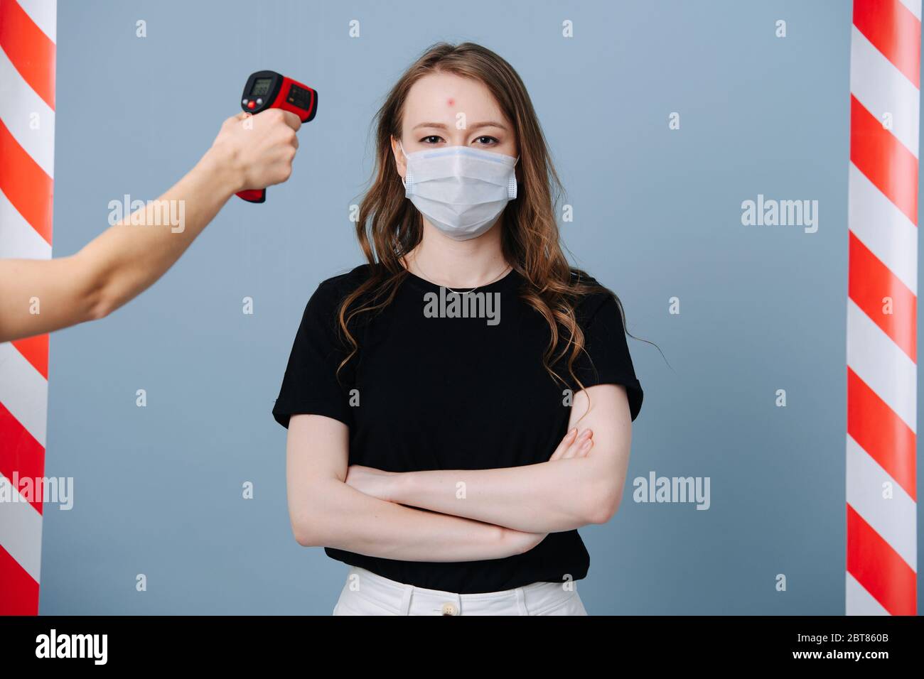 Girl stands at the epidemic control point, staff measures her temperature Stock Photo