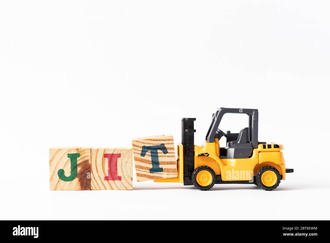 Toy forklift hold wood letter block T to complete word JIT (Abbreviation of Just in time) on white background Stock Photo