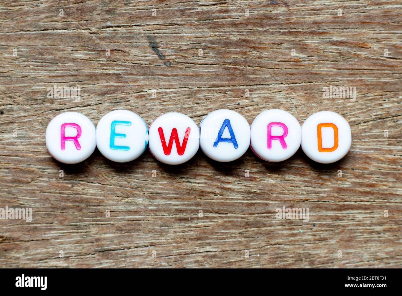White bead with color letter in word reward on wood background Stock Photo