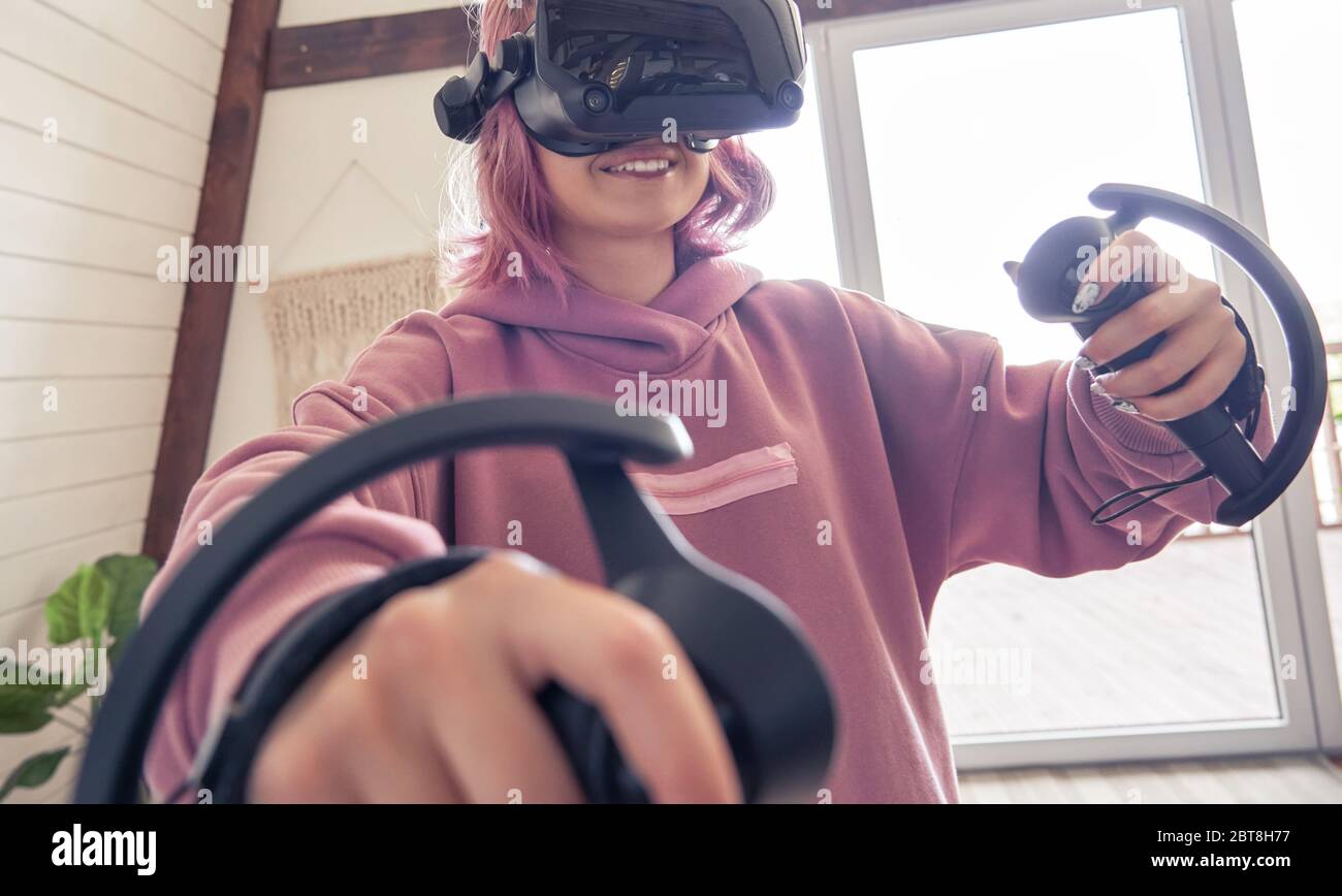 Young adult woman wear vr headset hold controllers play immersive video