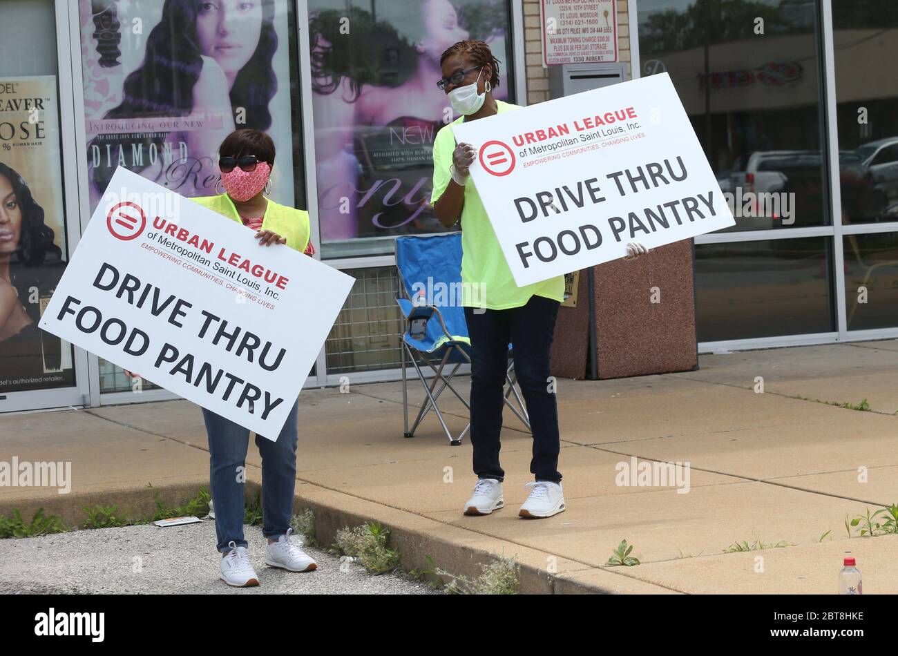St. Louis, United States. 23rd May, 2020. Volunteers walk to their work space with signs at the St. Louis Urban League's food give-a-way in St. Louis on Saturday, May 23, 2020. The 3300 cars that will get food will receive enough food to feed a family of four for several days. This event is the eighth food give-a-way put on by the Urban League. Many are in need of the food due to the coronavirus. Photo by Bill Greenblatt/UPI Credit: UPI/Alamy Live News Stock Photo