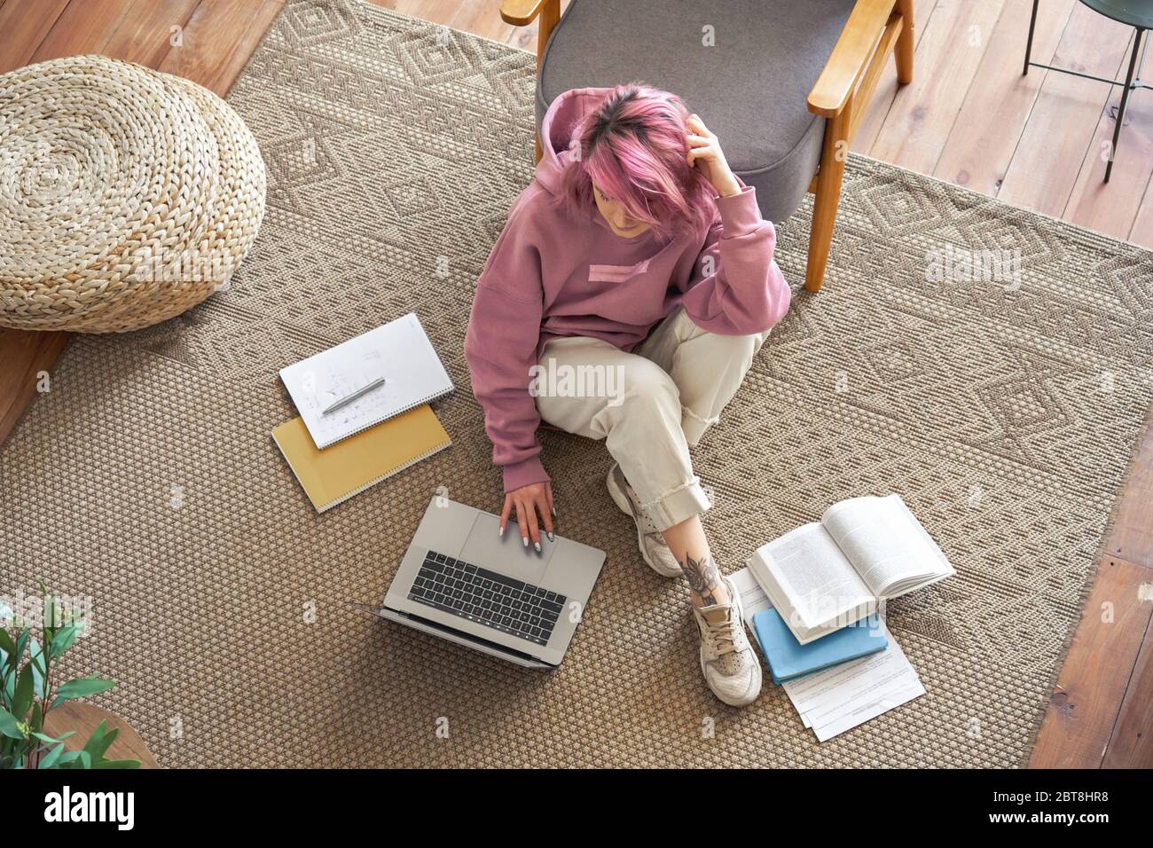 Teen girl school student pink hair using laptop sit on floor elearning top view. Stock Photo