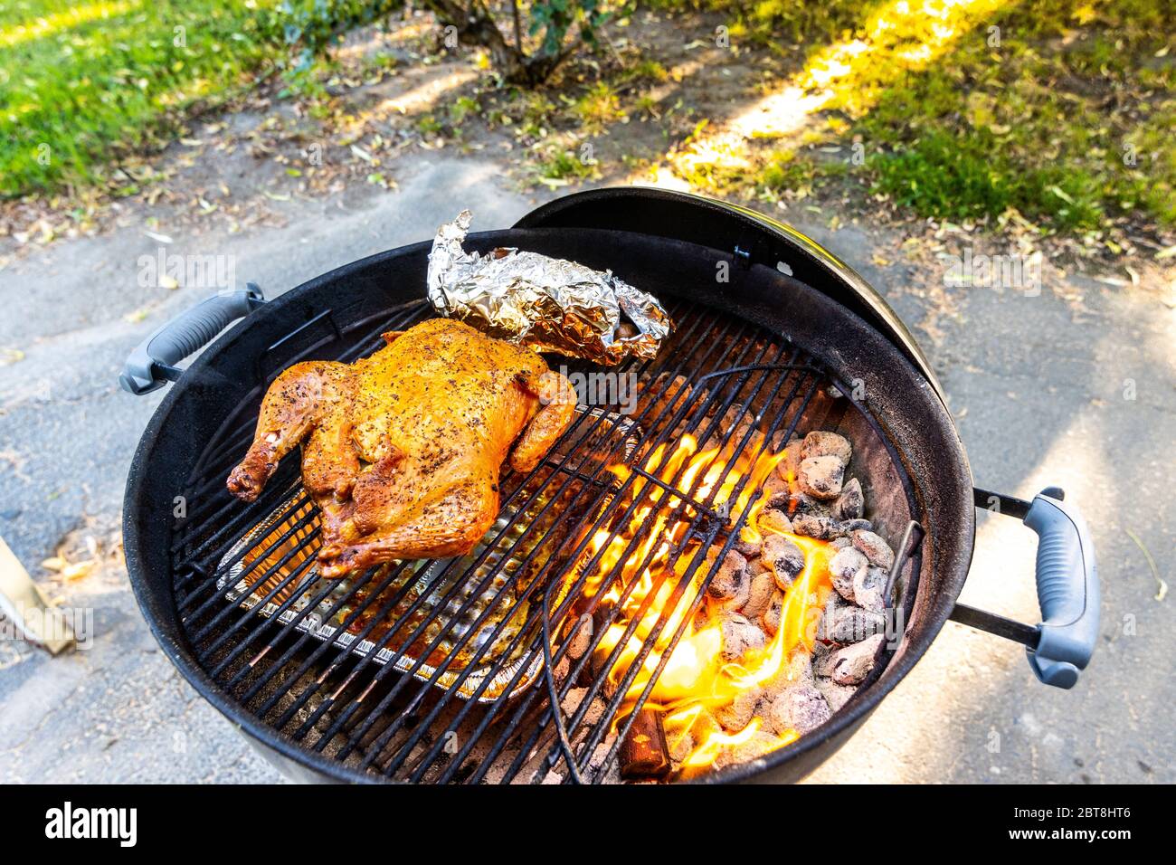 A Whole Chicken Being Smoked With Applewood On A Weber Kettle Barbecue With A Packet Of Potatoes And Carrots Stock Photo Alamy