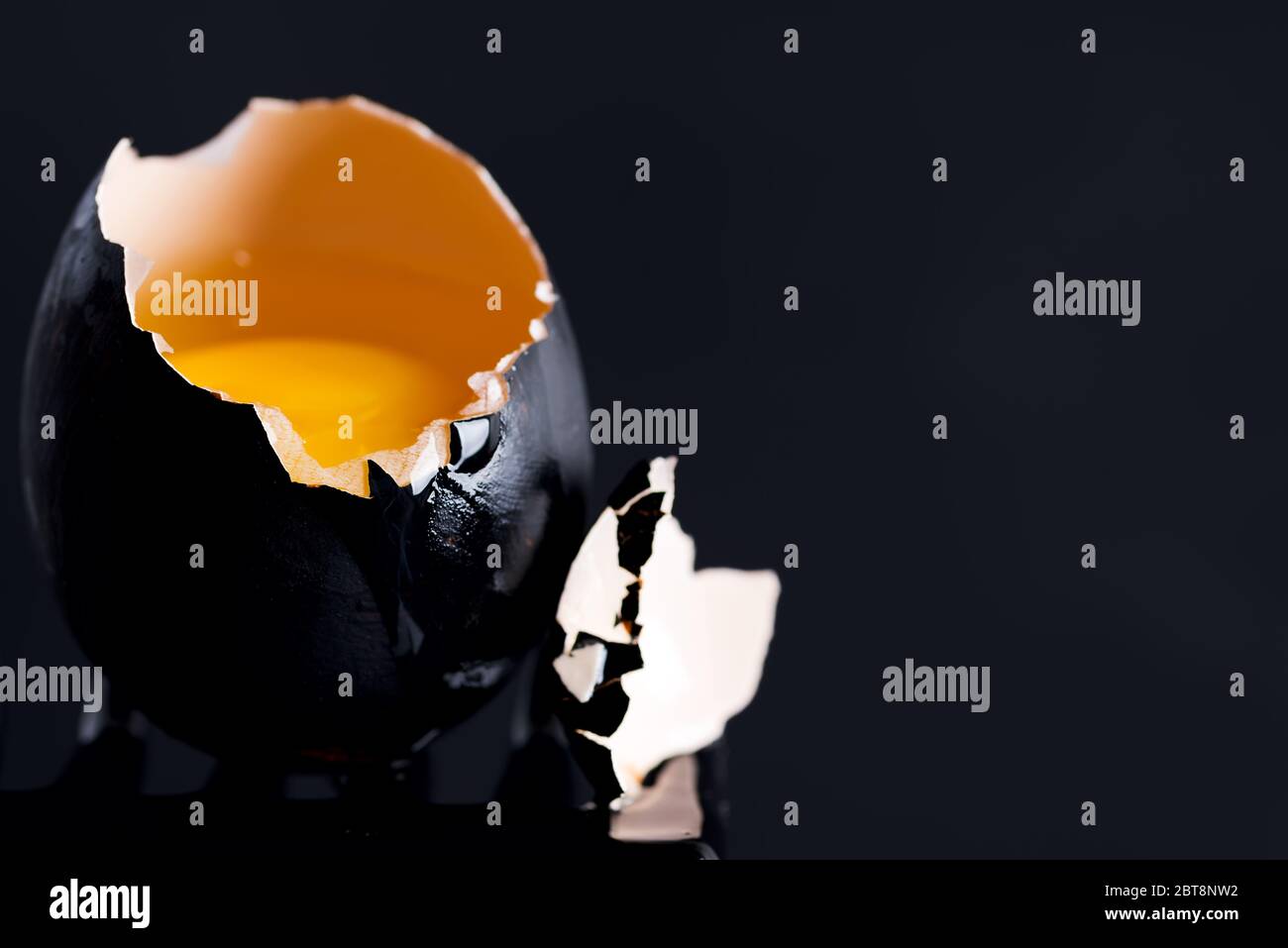 Black egg with yolk and drops on the edge of a black background Stock Photo Alamy
