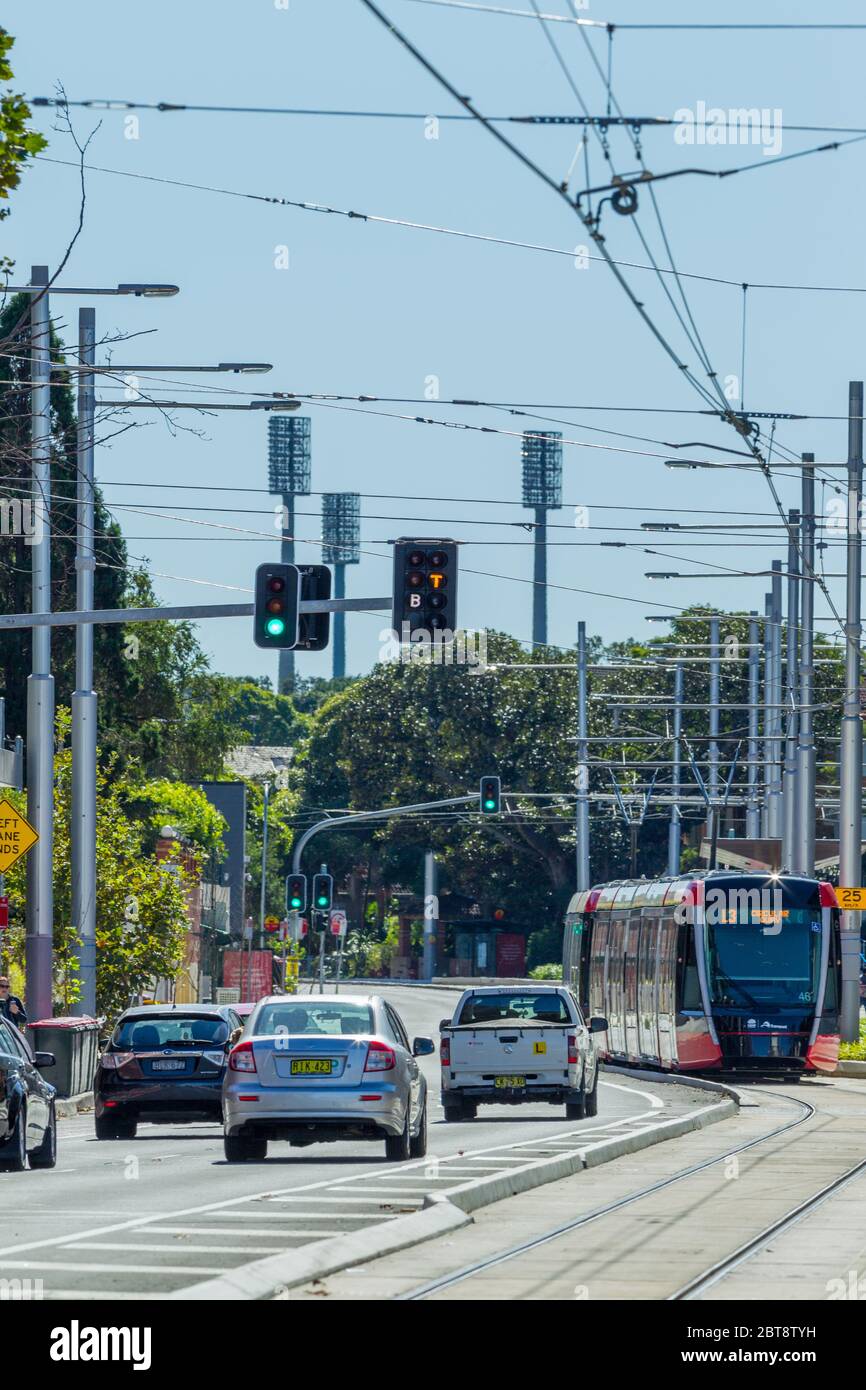 Traffic and a Sydney Light Rail tram on Anzac Parade in Kensington, Sydney, Australia, with the lights of the SCG (Sydney Cricket Ground) seen in the background. Stock Photo