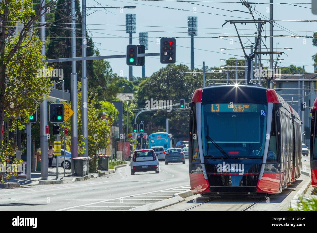 Traffic and a Sydney Light Rail tram on Anzac Parade in Kensington, Sydney, Australia, with the lights of the SCG (Sydney Cricket Ground) seen in the background. Stock Photo