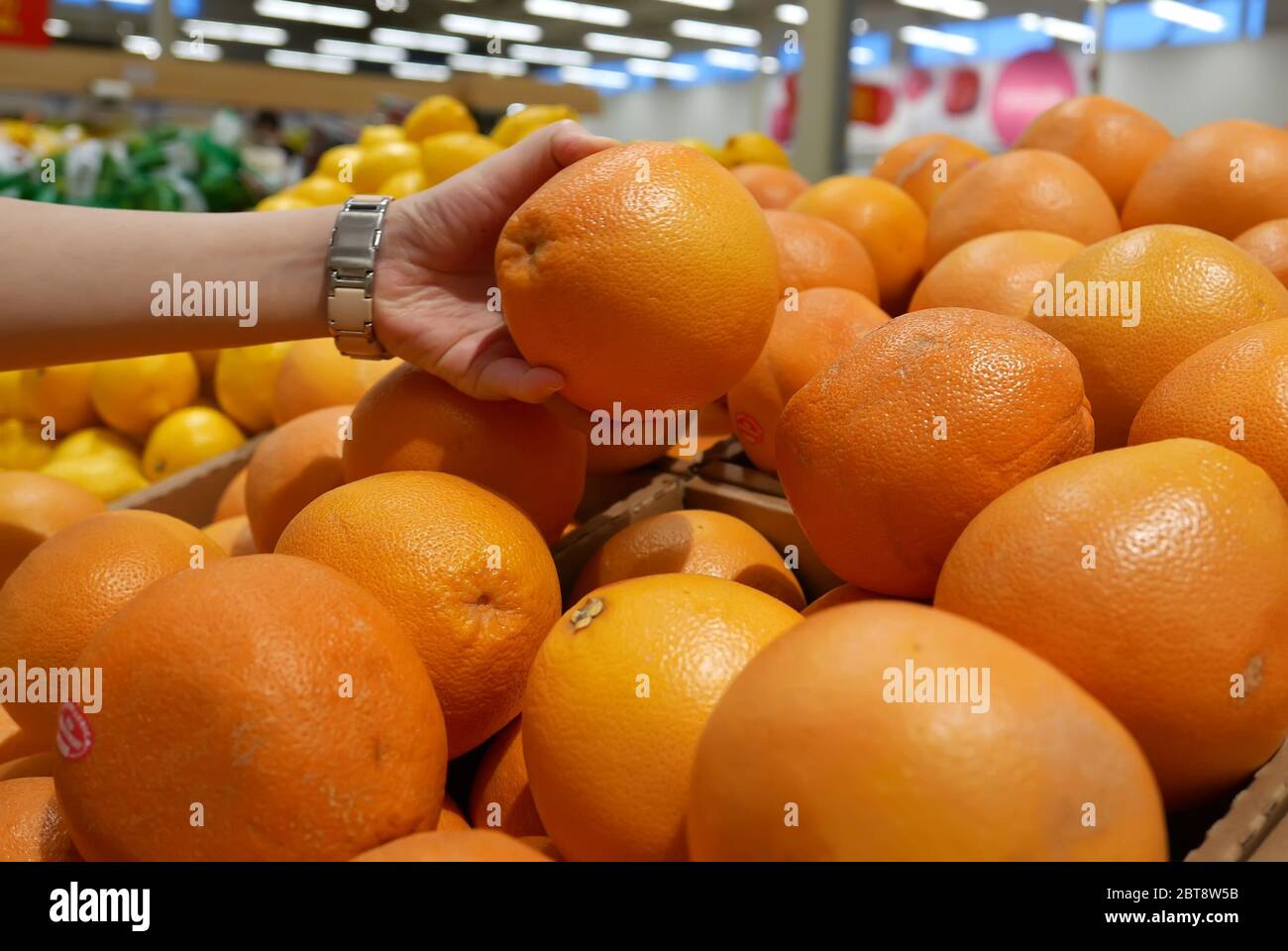 Motion of woman's hand picking grapefruit inside superstore Stock Photo