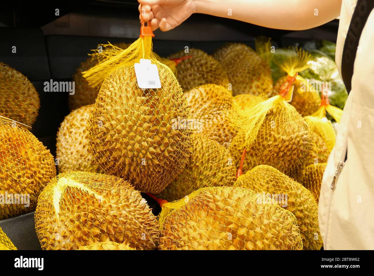 Motion of woman's hand picking durian inside superstore Stock Photo