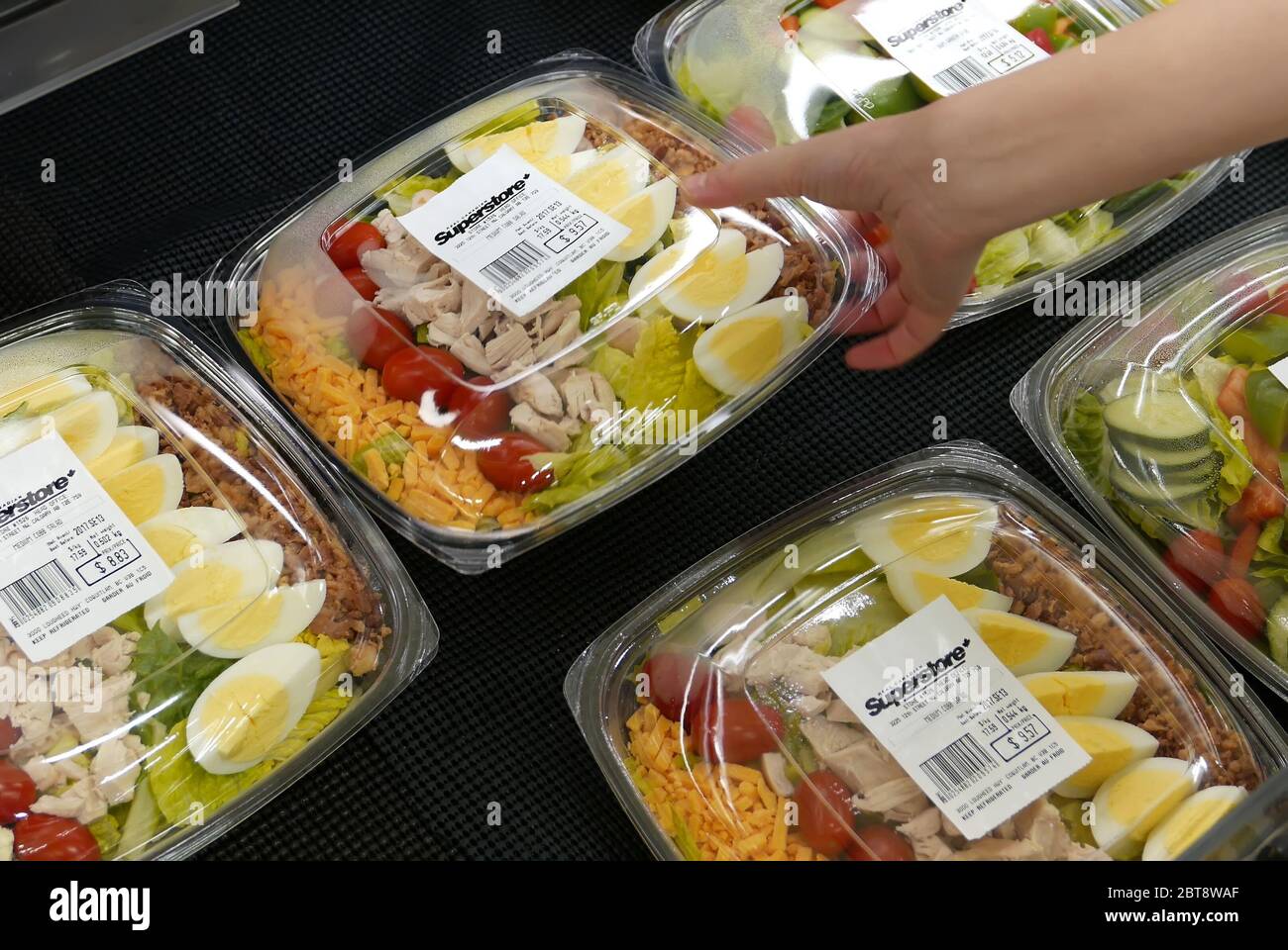 Motion of woman's hand picking salad inside superstore Stock Photo