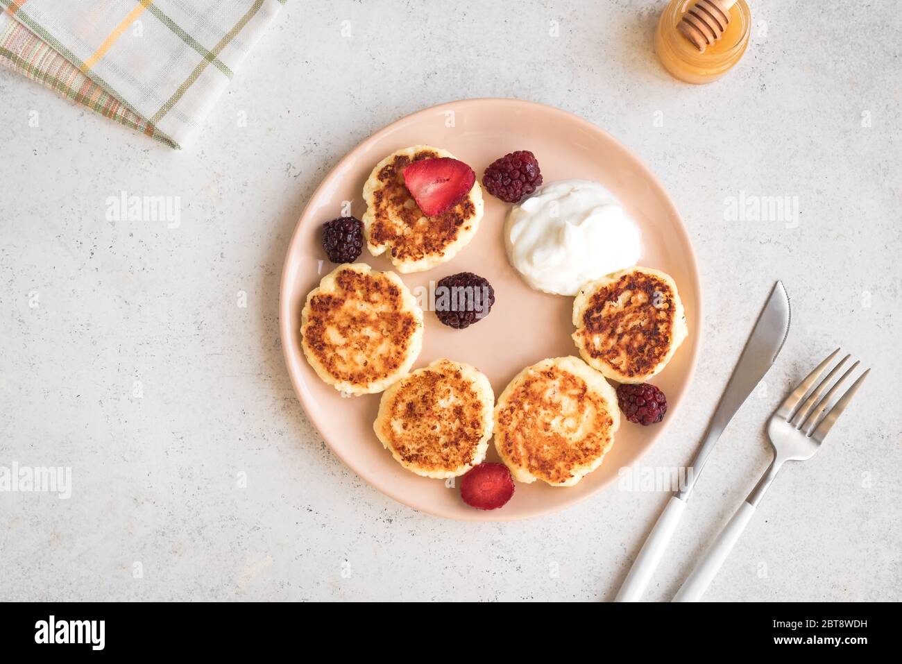 Cottage cheese pancakes  (syrniki, curd fritters) for breakfast. Fresh homemade cheese pancakes on white background, top view, copy space. Stock Photo