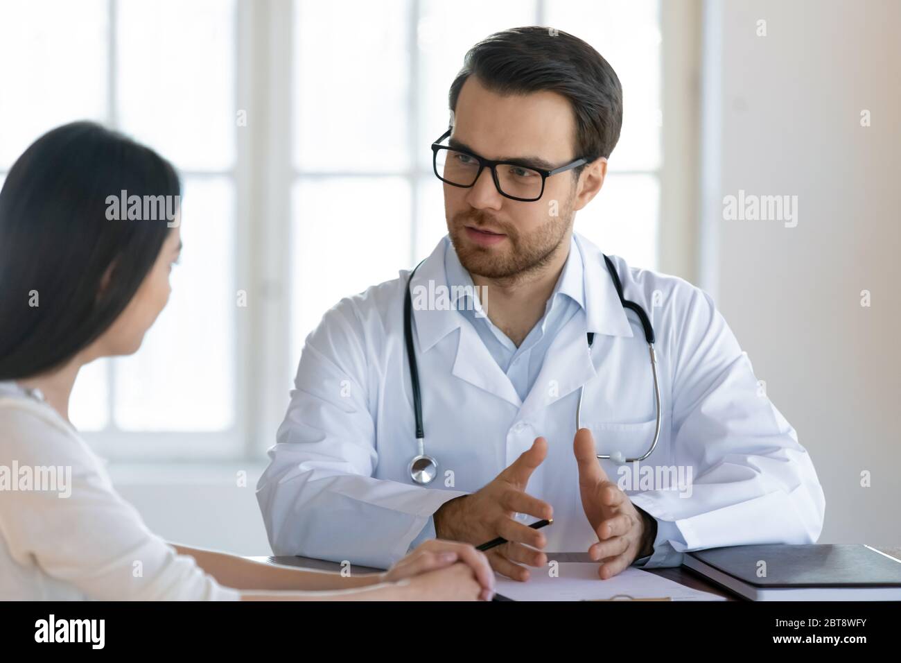 Male GP talk at consultation with female client Stock Photo