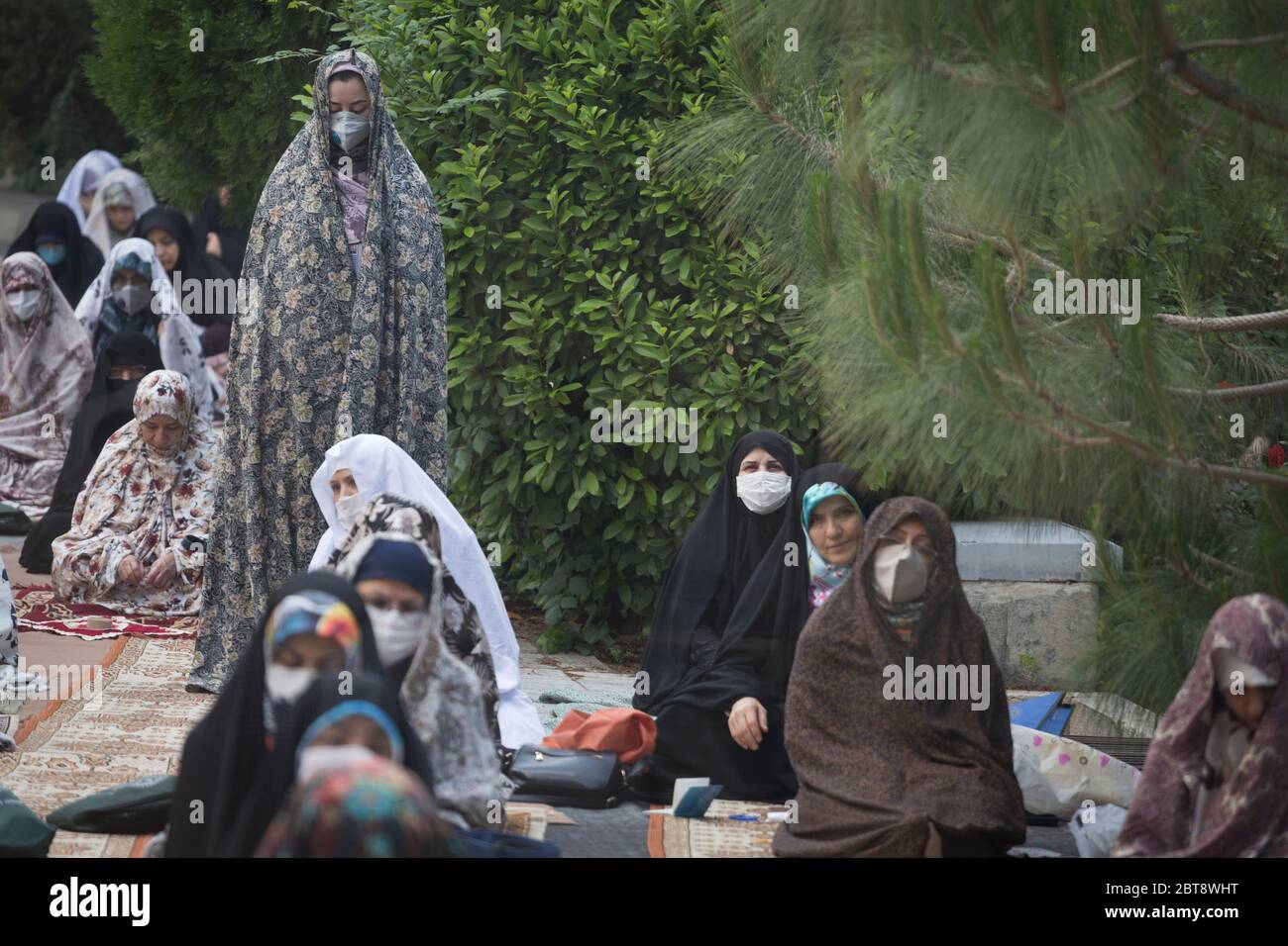 May 24, 2020, Tehran, Iran: Shia Muslims wearing protective face masks prepare to offer Eid al-Fitr prayers marking the end of the Islamic fasting month of Ramadan following the spread of the new coronavirus (COVID-19), at Tehran University Campus Mosque, in Tehran, Iran. Muslims worldwide celebrate one of their biggest holidays under the long shadow of the coronavirus, with millions confined to their homes and others gripped by economic concerns during what is usually a festive time of shopping and celebration. In Iran, which has endured the deadliest outbreak in the Middle East, authorities Stock Photo