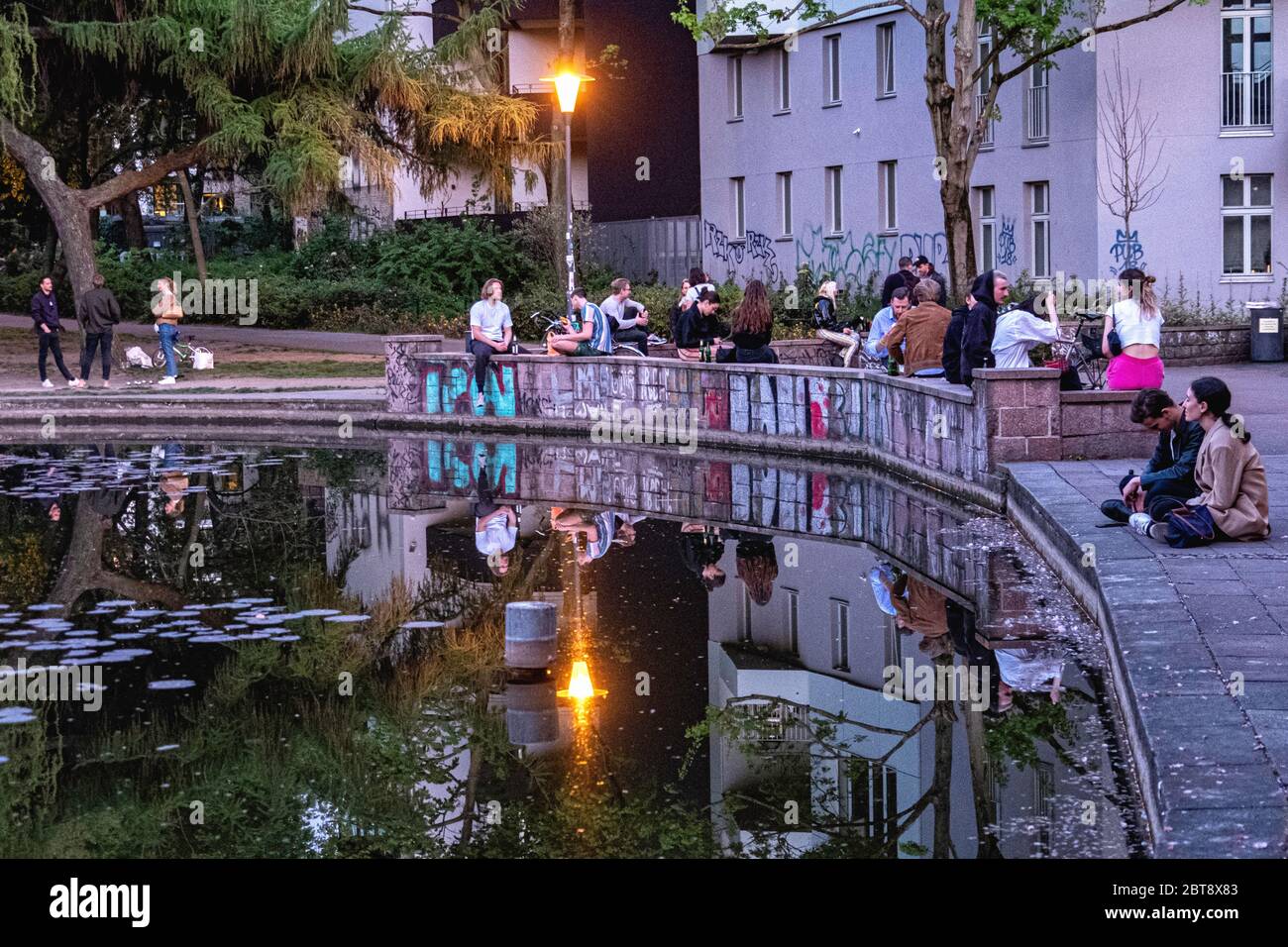 People sitting next to pond in Weinberspark in Mitte, Berlin during the Corona pandemic Stock Photo