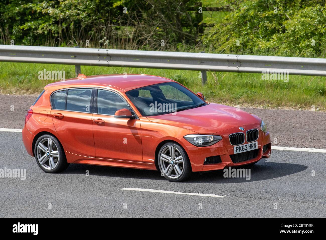 2013 orange BMW 116I M Sport; Vehicular traffic moving vehicles, cars driving in England, travelling vehicle on UK roads, motors, motoring, motorists on the M6 motorway highway in Manchester. Stock Photo