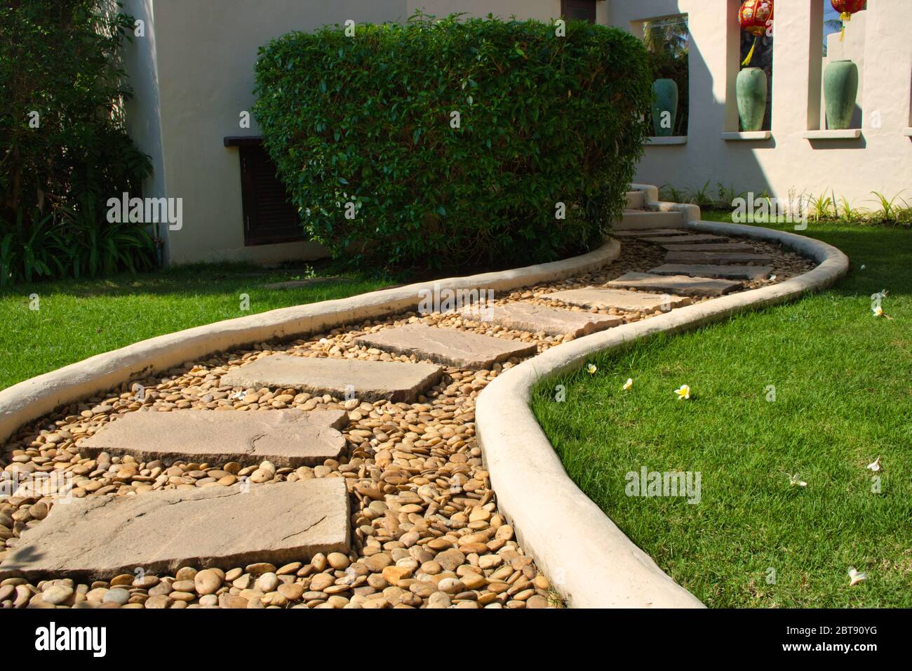 This unique photo of a beautiful curvy stone path through a meadow in a garden. the picture was taken in thailand Stock Photo