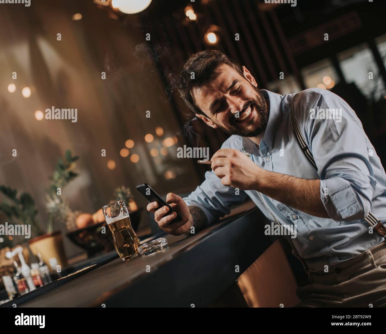 Young man drinking beer and smoking cigarette at the pub Stock Photo ...