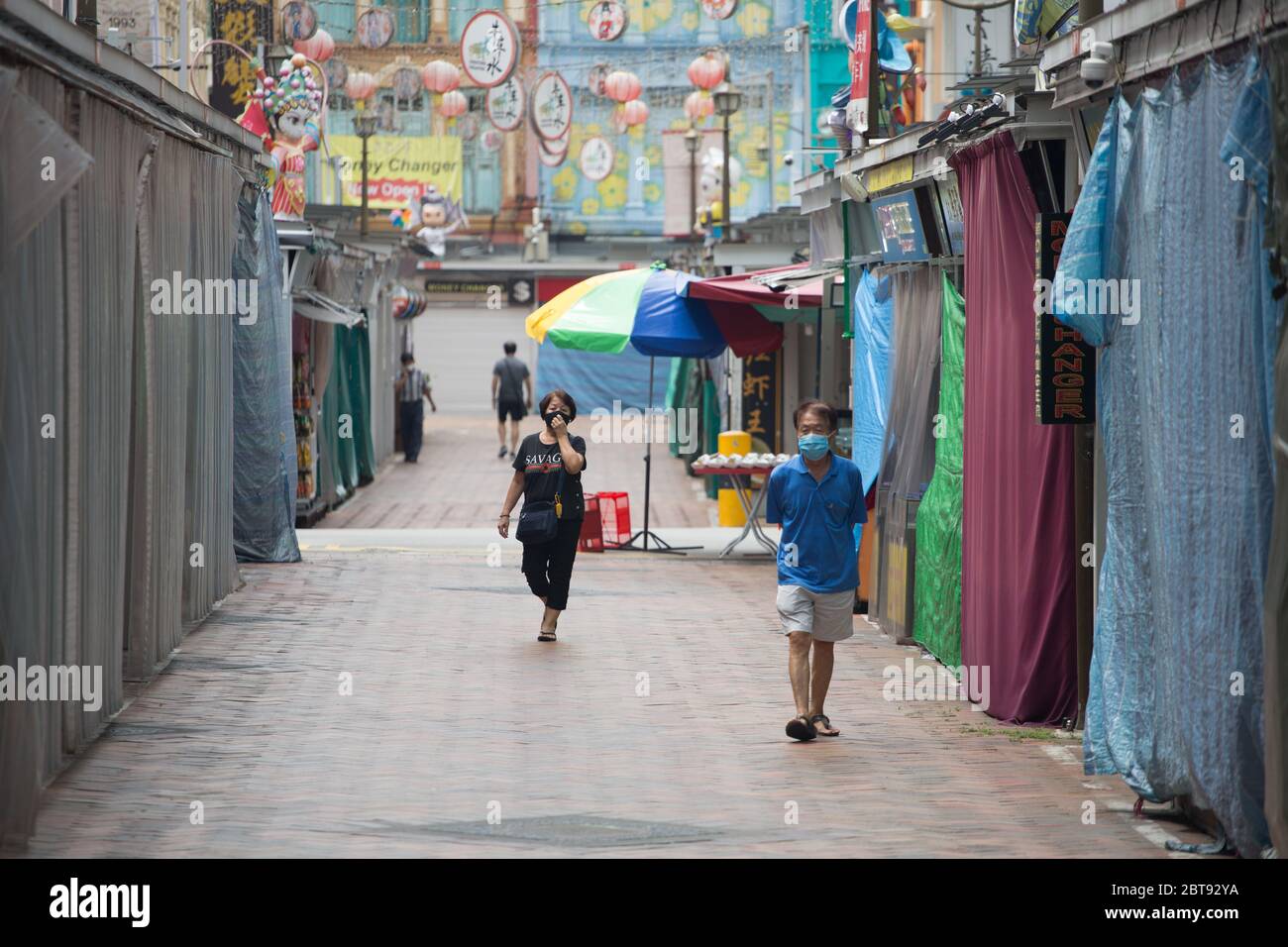 During the pandemic situation. Few folks wearing a mask roamed on the pale street at Chinatown, Singapore Stock Photo